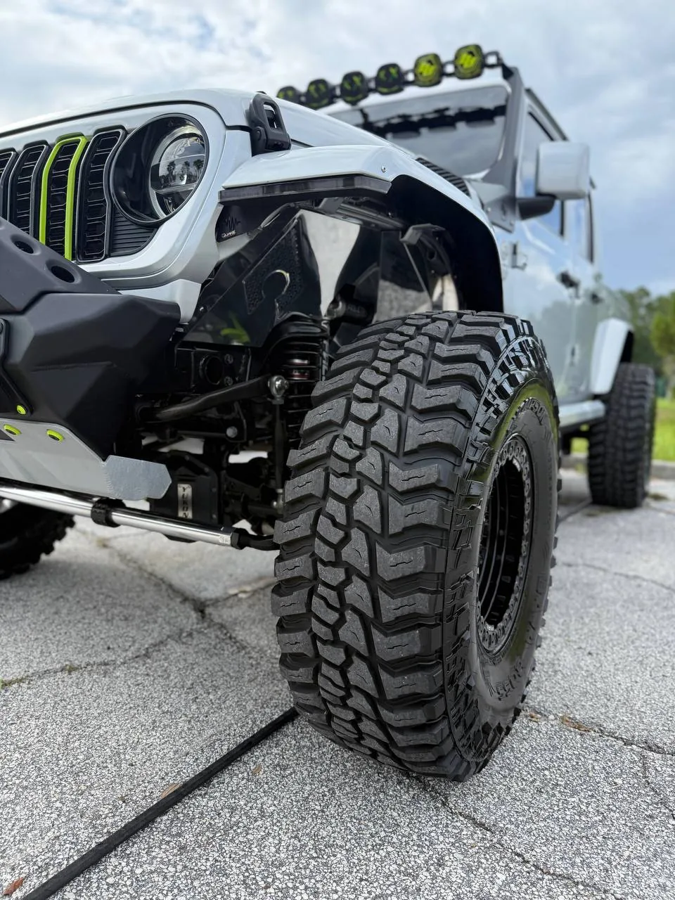 Close-up of massive off-road tire and green accents on gray Gladiator