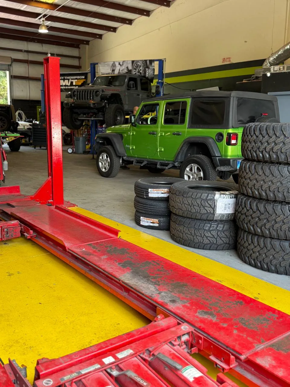 GUS4X4 Jeeps shop with Gladiator on lift and green Wrangler